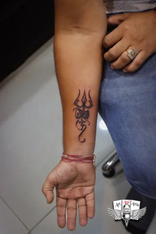 Trishul Forearm Tattoo Design | Art and Artist Tattoo Shop Trishul tattoo on forearm done at Art and Artist Tattoo Shop, clean and minimal black ink tattoo design