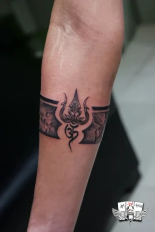 Trishul Om Armband Tattoo in Tattoo Raipur | Art and Artist Tattoo Studio Trishul Om armband tattoo on arm done at tattoo raipur studio with detailed black and grey shading