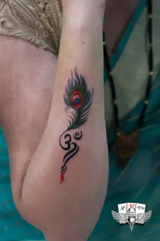 Peacock Feather Om Tattoo in Tattoo Raipur | Art and Artist Tattoo Studio Peacock feather Om tattoo on arm done at tattoo raipur studio with vibrant color detailing
