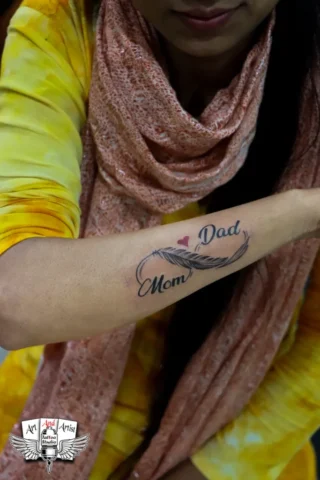 Mom Dad Feather Tattoo in Tattoo Raipur | Art and Artist Tattoo Studio Mom dad feather tattoo on forearm done at tattoo raipur studio with fine line black ink