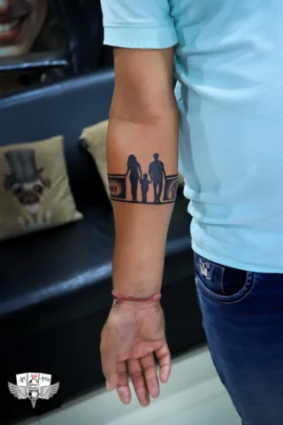 Family Armband Tattoo in Tattoo Raipur | Art and Artist Tattoo Studio Family silhouette armband tattoo on arm done at tattoo raipur studio with bold black ink